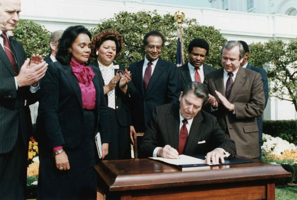 In the presence of Coretta Scott King (2nd from left), President Ronald Reagan signs a bill making Martin Luther King Jr.'s birthday a national holiday.